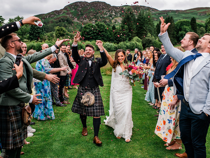 Bride and groom celebrate as they walk back down aisle through confetti thrown by their loved ones